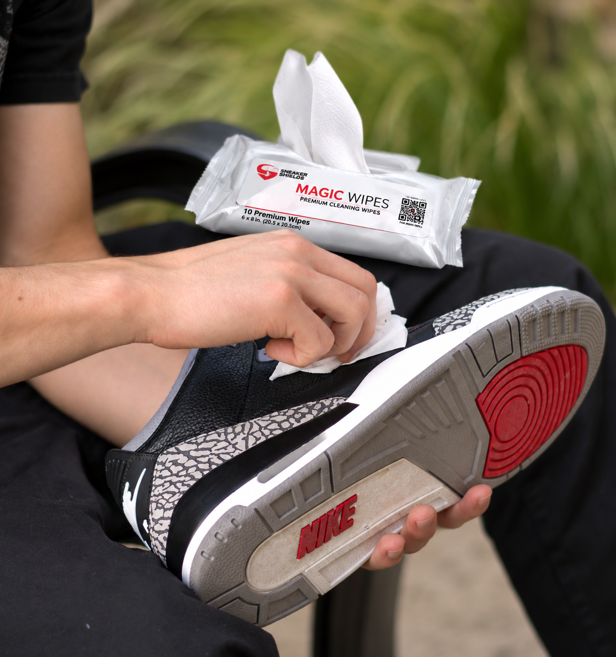 Magic Wipes cleaning a sneaker midsole and outsole outdoors, pack resting on the knee